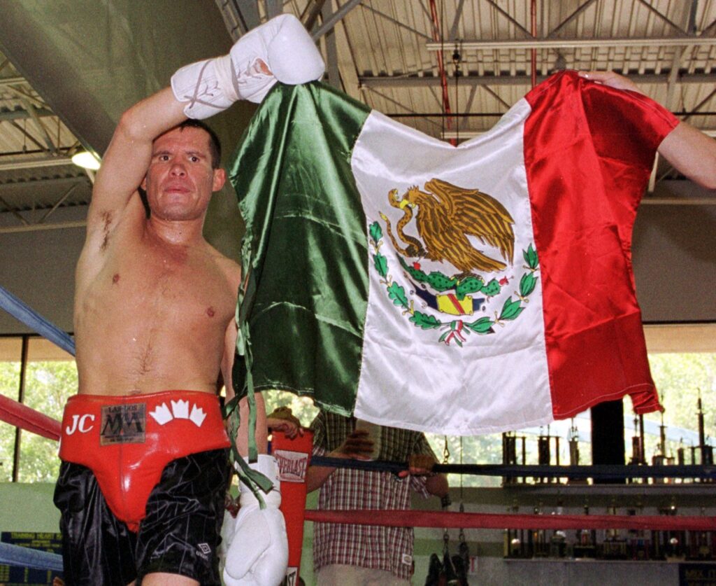 SCOTTSDALE, AR - JULY 24: Mexican boxing legend Julio Cesar Chavez (L) displays his national flag during a workout at a gym 24 July 2000 in Scottsdale, Arizona. Chavez will attempt to regain his WBC superlightweight title when he takes on Russian-born Konstantin Tszyu, who is now based in Australia, on July 29 in Phoenix. (Photo credit should read MIKE FIALA/AFP/Getty Images)