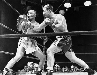 23 Sep 1952, Philadelphia, Pennsylvania, USA --- Original caption: 9/24/52-Philadelphia, Pennsylvania: INP photographer Herb Scharfman was as precisely "on the button" as was the challenger when Rocky Marciano drove his right mercilessly to the jaw of champion Joe Walcott to knock him from his throne in the 13th round of last night's title fight at Philadelphia's Municipal Stadium. A cloudy spray of water and perspiration makes a partial halo around the head of the champion who was "ex" eleven seconds later. Note the "mouse" under Marciano's left eye. Ph: Herb Scharfman --- Image by © Bettmann/CORBIS